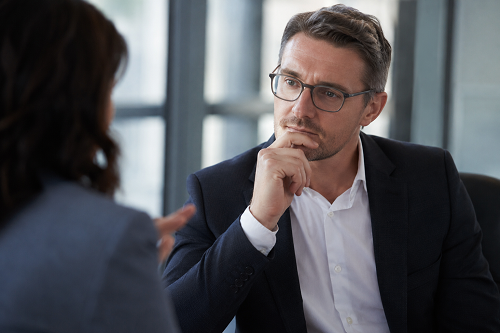Executive leader reflecting thoughtfully during a feedback discussion