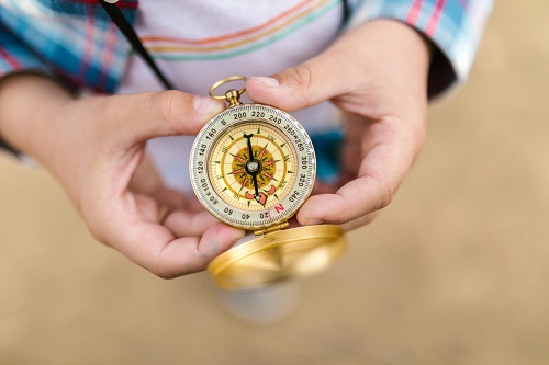 A person holding a compass to represent the six compasses for business development.