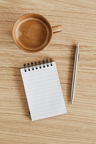 An open journal with actionable plans, a pen, a cup of coffee, and a tidy workspace illuminated by natural light, symbolizing goal setting and focus.