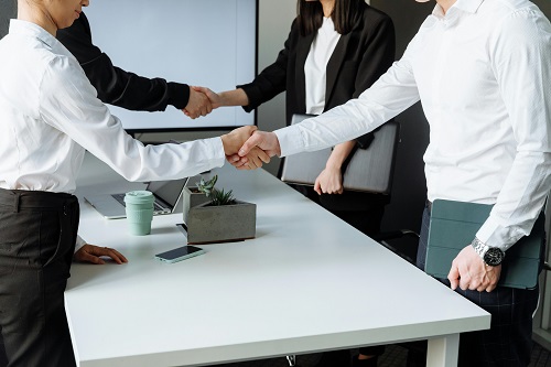 Professionals shaking hands across a negotiation table, symbolizing a successful business deal.