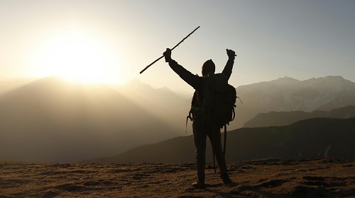 A person standing on a mountain peak at sunrise, celebrating their passion and purpose.