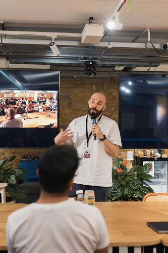 A confident public speaker making eye contact and engaging with an audience in a conference setting.