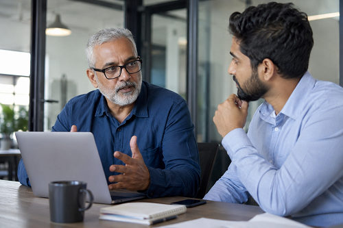 Experienced business mentor speaking with SME founder in office