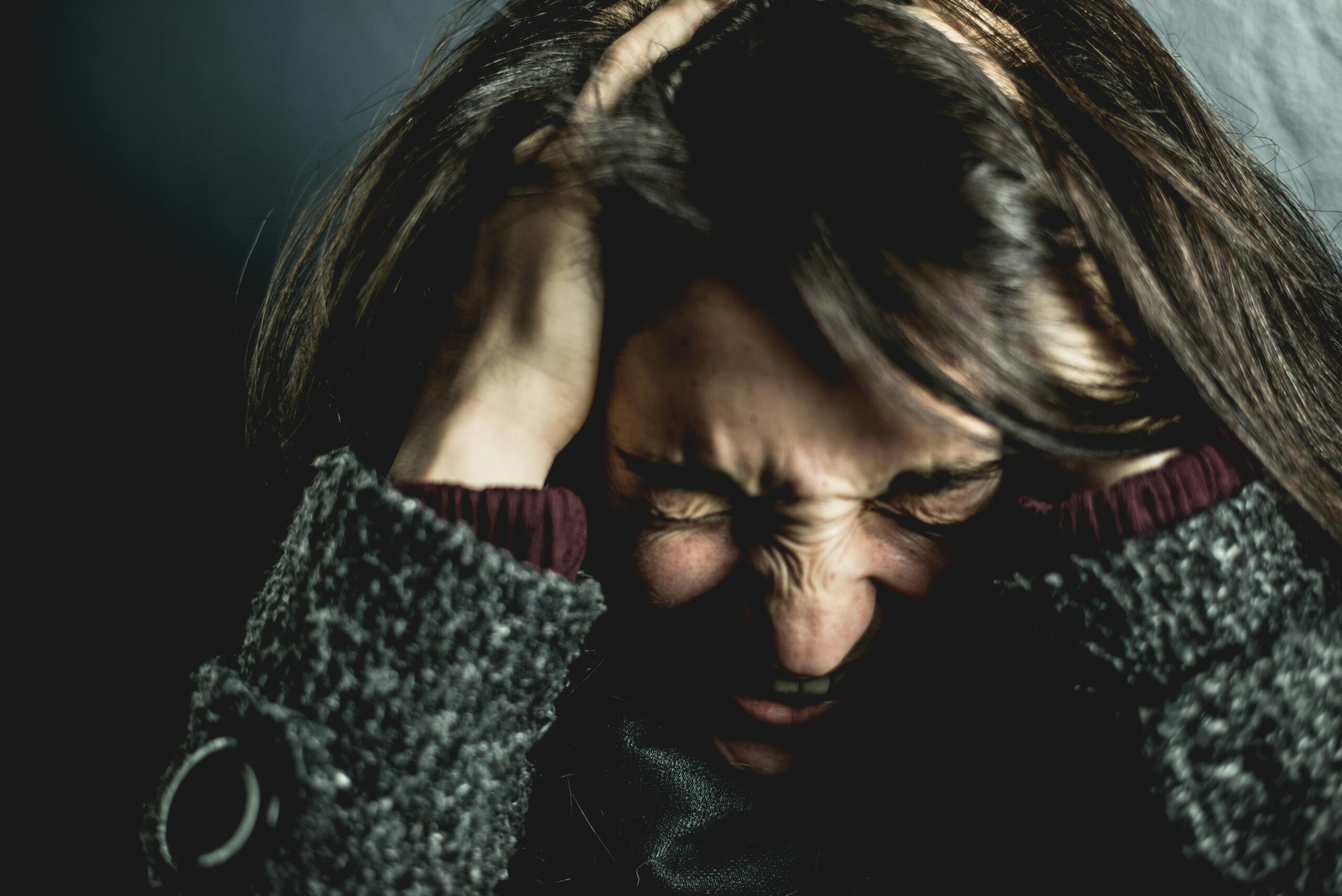 A woman holding his head seemingly overwhelmed by emotions to represent a guide to help you mastering your emotions