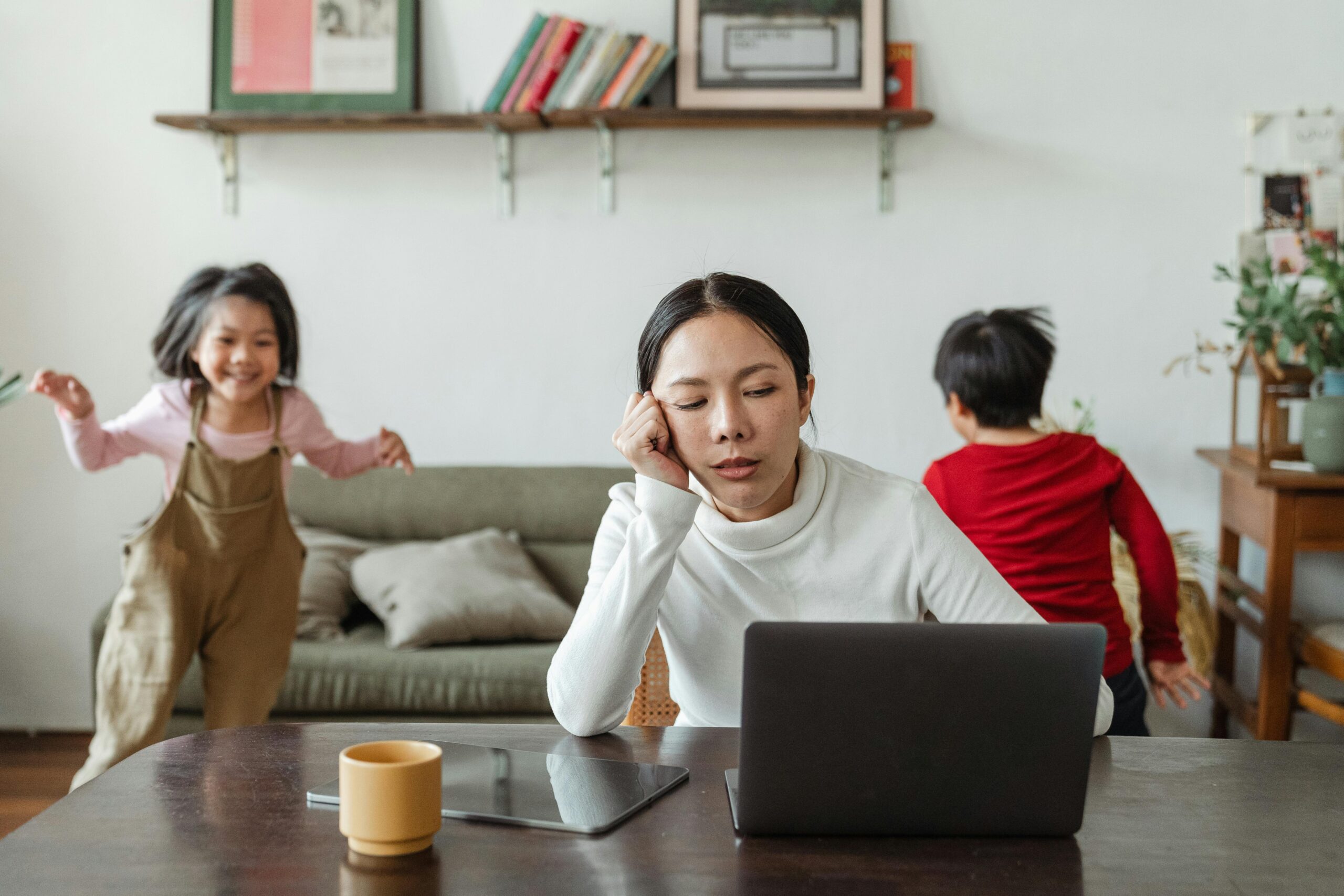 A woman working with children playing in the background symbolizing how to manage multiple responsibilities