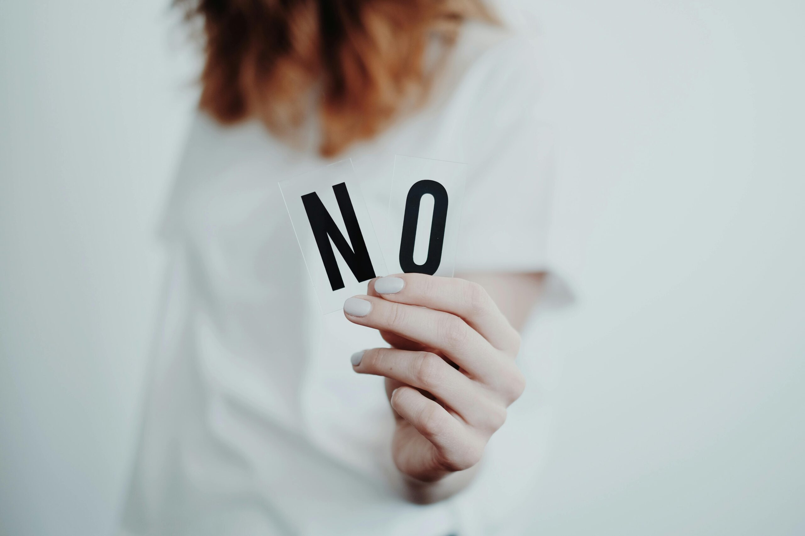 a woman holding two letters that read NO is one way of setting better boundaries